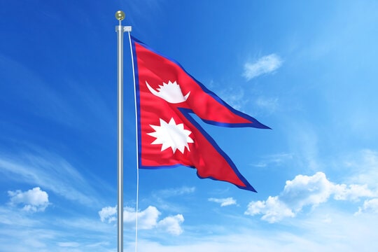 beautiful-picture-of-nepal-flapping-over-the-winds-min Nepal flags fluttering in the sky with a backdrop of blue and white clouds.