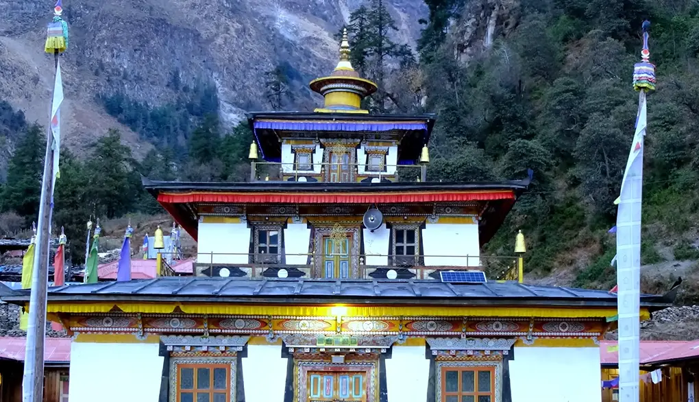 Beautiful traditional Gompa with colorful prayer flags nestled against a mountain backdrop on the way to Deng village along the Manaslu Circuit Trek.