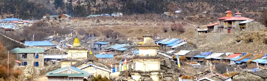 A peaceful village nestled in the hills, with stone houses, winding paths, and scenic mountain views in the background.