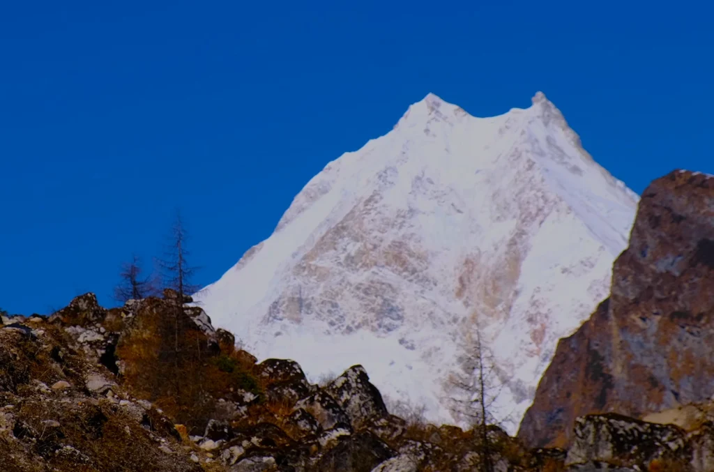 Majestic view of snow-capped Manaslu Peak towering above rugged Himalayan terrain during the Manaslu Circuit Trek.