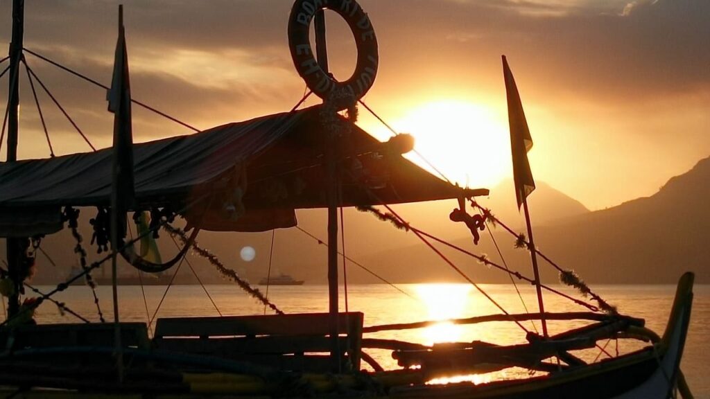 Golden sunset casting warm hues over traditional boats gently floating on calm waters.