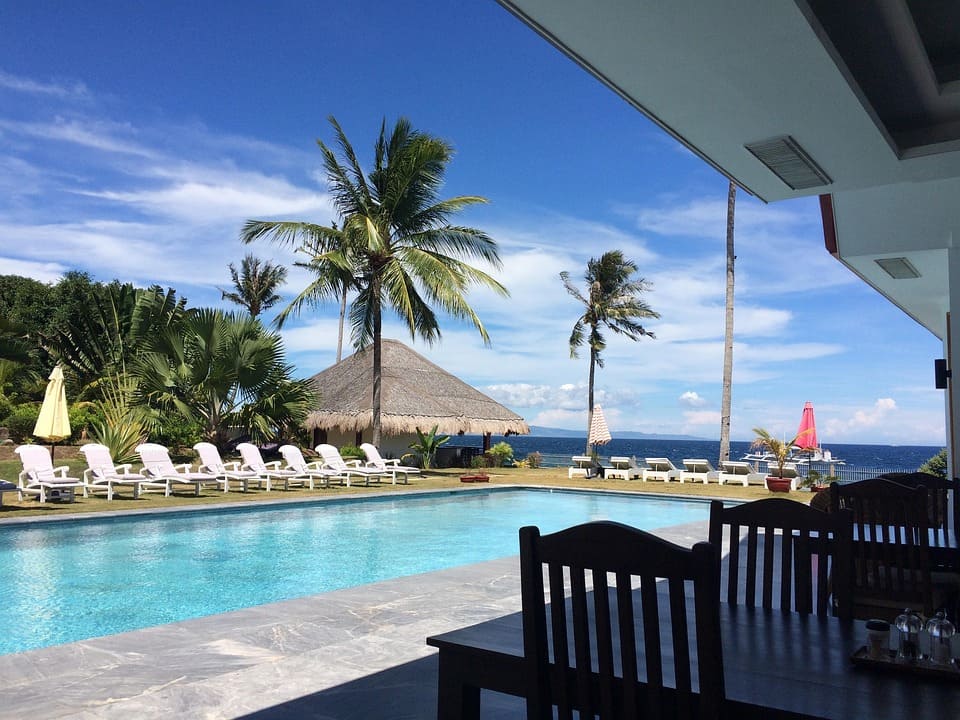 accommodations-in-philippines (1) Luxury beachfront resort in the Philippines with overwater villas and palm trees.