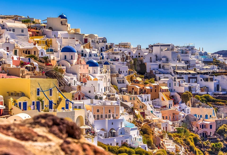 santorini-greece Santorini, Greece, stunning whitewashed houses with blue domes overlooking the Aegean Sea.