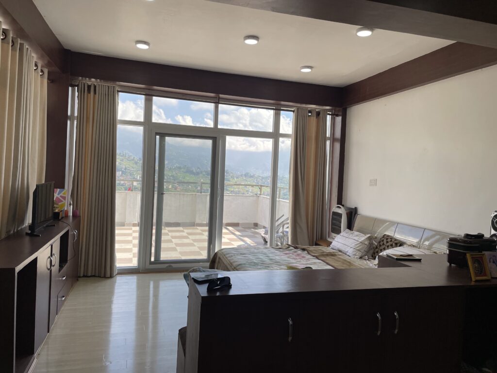 Apartment bedroom with private balcony in Tarkeshwar, Kathmandu, offering peaceful forest views.