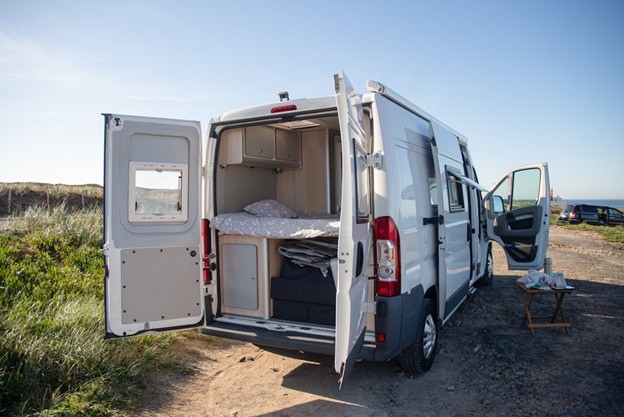 White passenger van parked on a scenic roadside, with clear skies in the background.