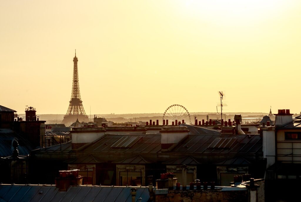 View of the Eiffel Tower in Paris, France, standing tall against a clear blue sky with surrounding cityscape at the base.