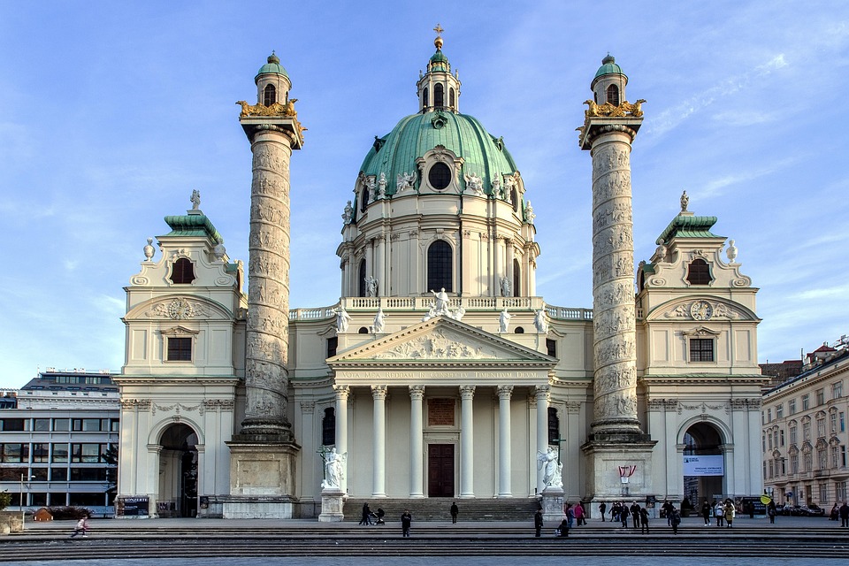 Elegant cityscape of Vienna, Austria, featuring historic buildings, grand palaces, and tree-lined streets under a clear sky.